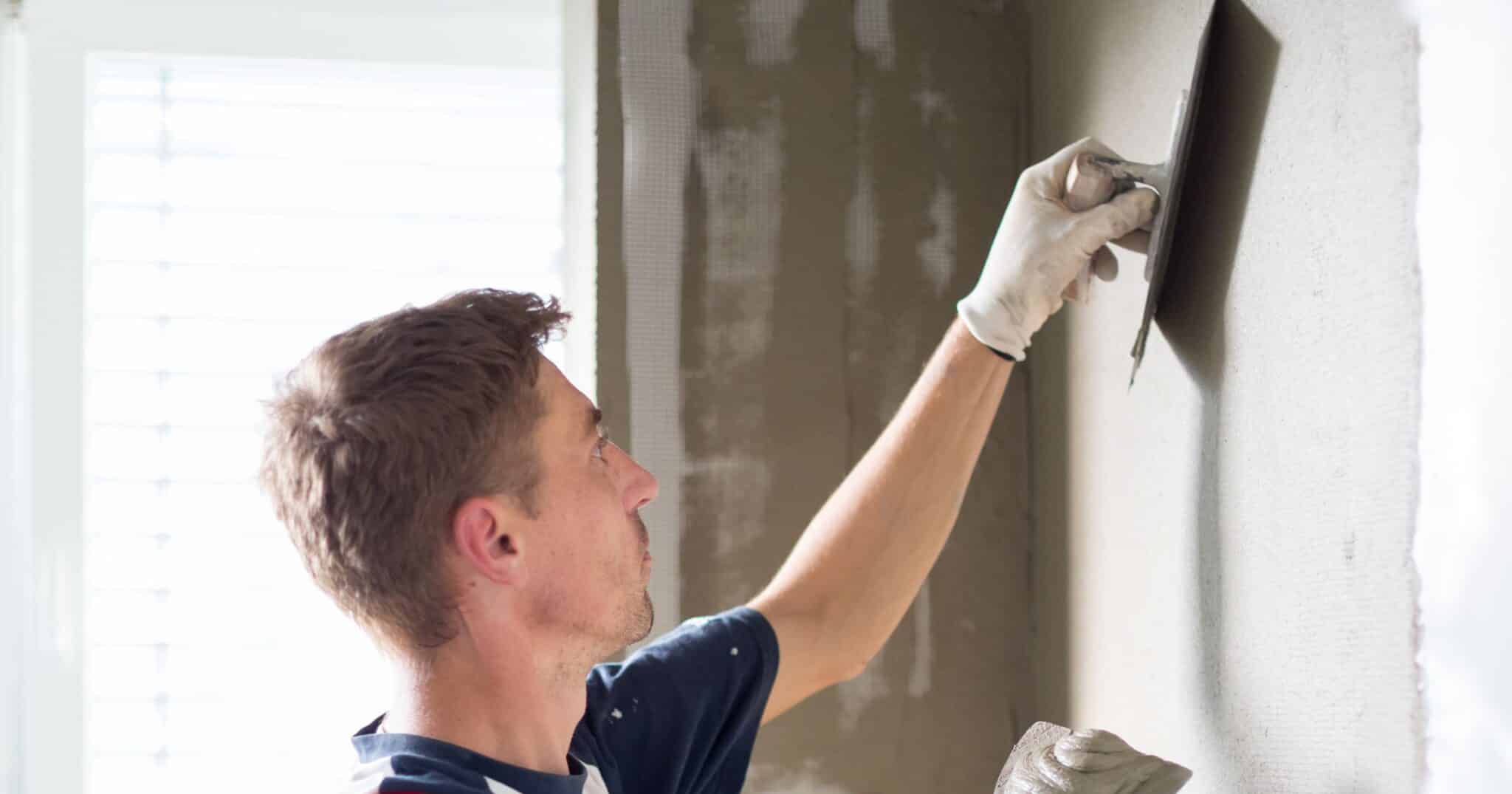 Plafonneur lissant un enduit intérieur à la taloche : c’est à ce stade, avant les finitions, que se contrôlent les tolérances du plafonnage